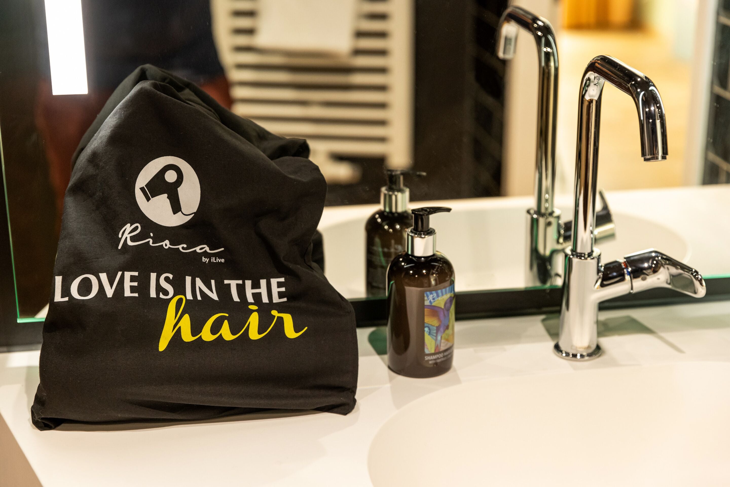 A black bag with a logo and text, a bathroom sink, and a faucet.