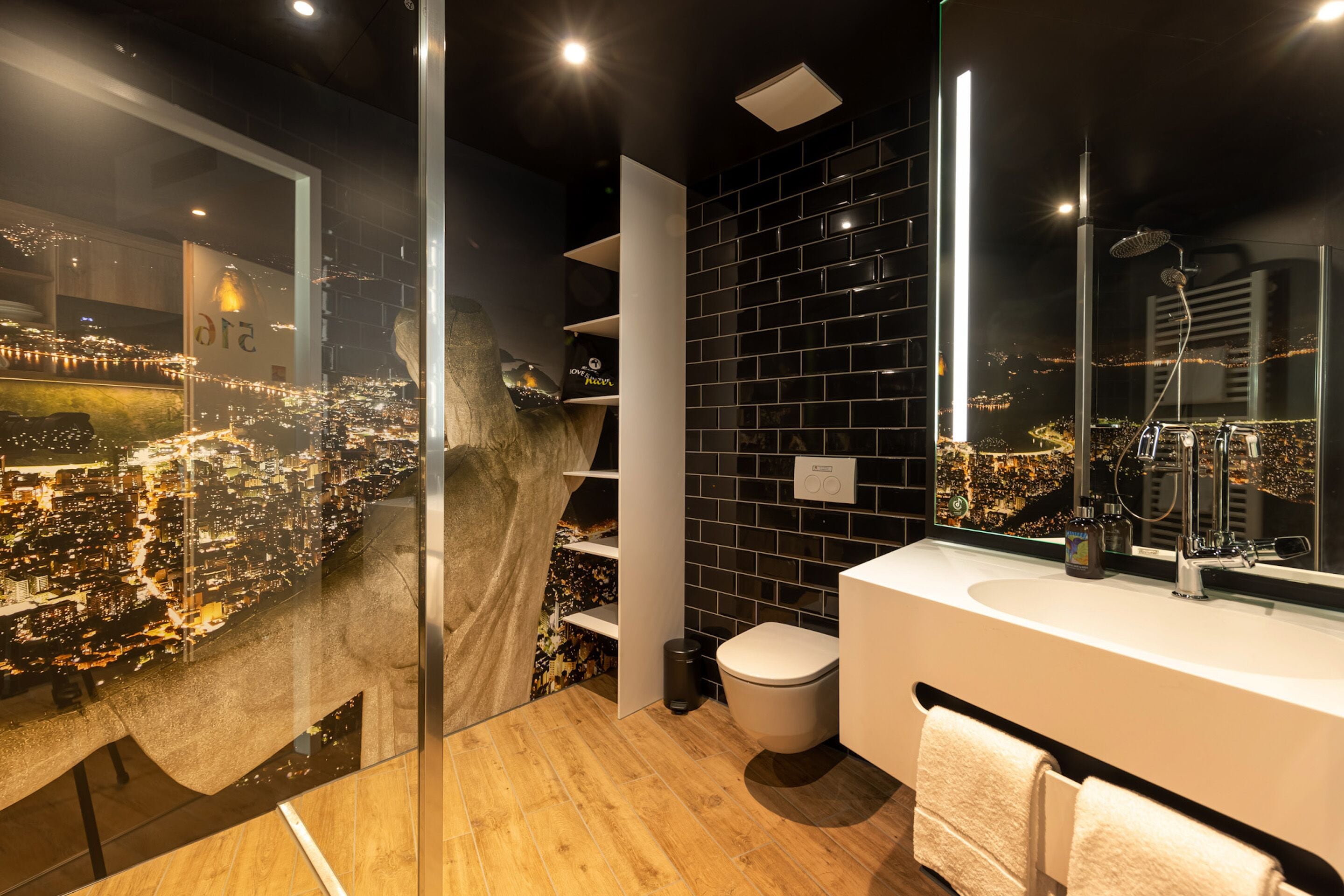 A modern bathroom with a city view, a large mirror, and a white sink.