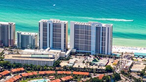Un hotel moderno con numerosi piani, spiaggia e area piscina.