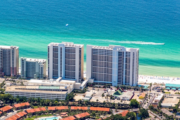 Un grand hôtel avec de nombreux étages, une plage et un parking.
