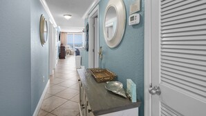 Un corridoio con vista sull'oceano, una porta con uno specchio e un tavolino con oggetti decorativi.