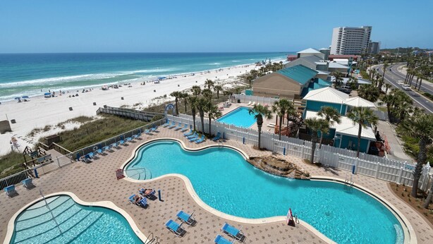 Un resort con un'ampia area piscina, una spiaggia e vista sull'oceano.