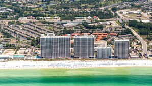 Un hotel sulla costa con tre edifici alti, una spiaggia e vista sull'oceano.