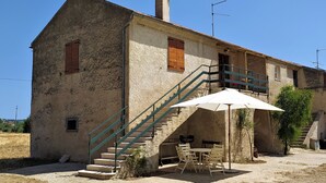 A rustic building with a staircase, outdoor seating, and a grill area. - Casolare Fonte di Moro (Abruzzo)