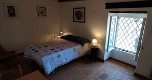 Et soveværelse med seng, et sengebord med lampe, et vindue med udsigt og en stol.