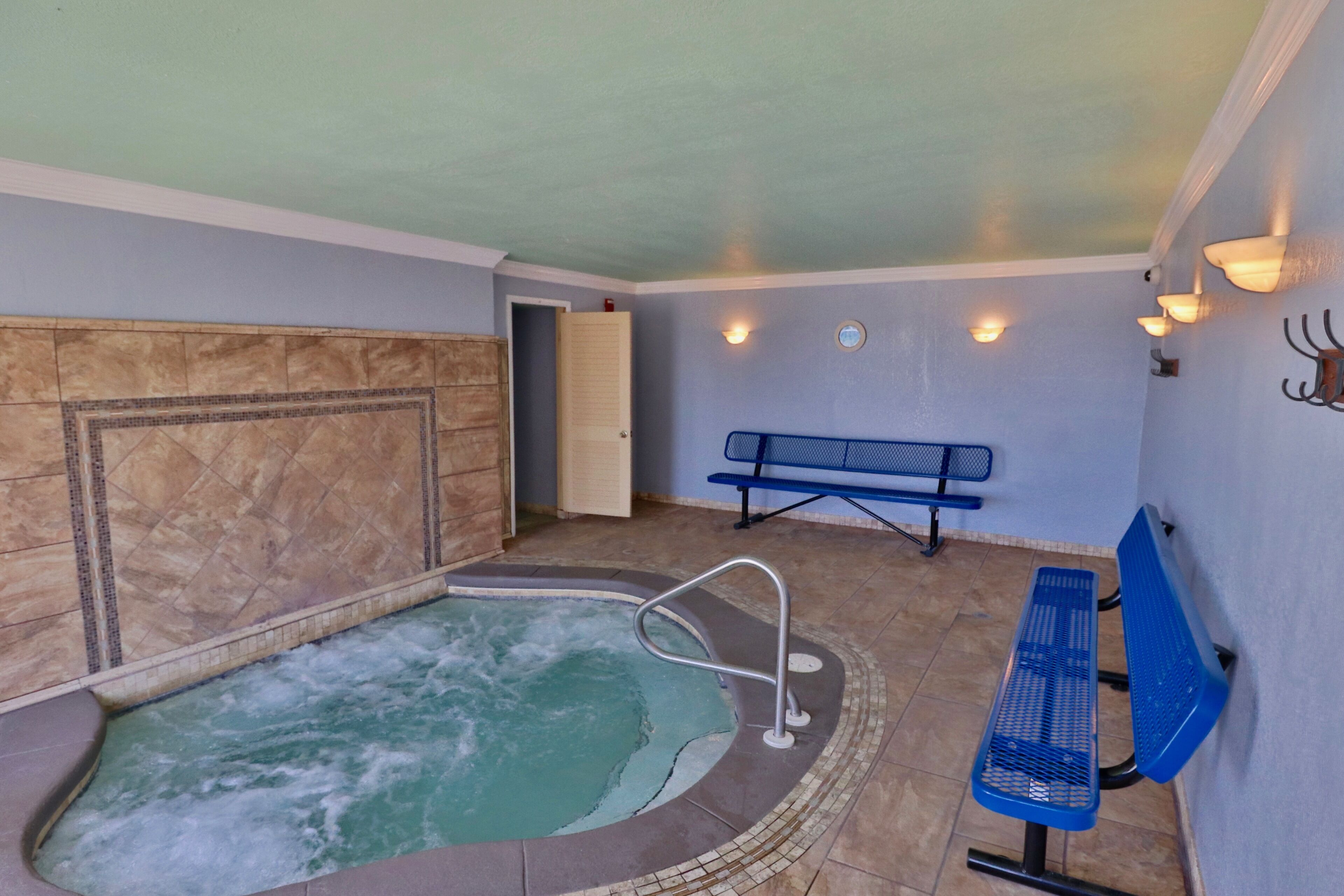 A spa room with a hot tub, a bench, and a wall-mounted light fixture.