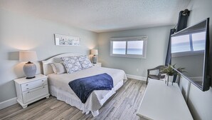 Un dormitorio con cama, mesitas de noche, cómoda, espejo y ventana con vistas.