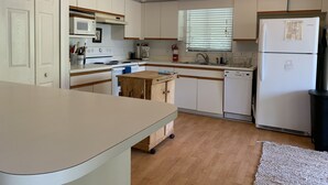 A compact kitchen with white cabinets, a microwave, a stove, a sink, and a refrigerator. - Private island getaway (Placida)