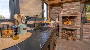 Eine Küche mit Kamin aus Backstein, einem Spülbecken und diversen Küchenutensilien.