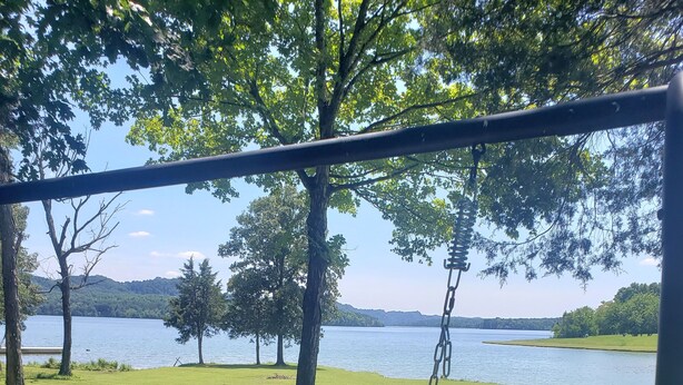 A wooden swing set overlooking a lake with a fire pit nearby. - Water front cottage w/water access, firepit & great sunsets. (Vonore)