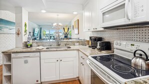 A modern kitchen with white cabinets, a built-in dishwasher, a stove, and a microwave.