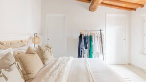 A bedroom with a bed, pillows, a hanging light fixture, a clothing rack, and a wardrobe. - Stylish Luxury Loft Sleeps 4 San Gimignano Tuscany (San Gimignano)