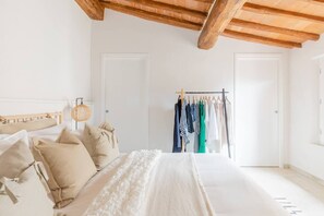 A bedroom with a bed, pillows, a hanging light fixture, a clothing rack, and a wardrobe. - Stylish Luxury Loft Sleeps 4 San Gimignano Tuscany (San Gimignano)