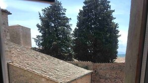 A view from a window overlooking a courtyard with stone buildings and a person walking. - Stylish Luxury Loft Sleeps 4 San Gimignano Tuscany (San Gimignano)