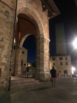 An ancient stone archway leading into a courtyard with a tall tower in the background. - Stylish Luxury Loft Sleeps 4 San Gimignano Tuscany (San Gimignano)