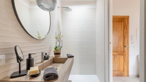 A modern bathroom with a wooden vanity, a round mirror, a shower, and a potted orchid. - Stylish Luxury Loft Sleeps 4 San Gimignano Tuscany (San Gimignano)