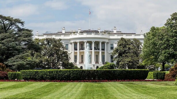 A large, white building with columns and a flag on top, surrounded by well-maintained lawns and trees. - Stylish Modern Suite in the Heart of Chevy Chase! (Washington)