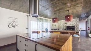 Un interno di un caffè moderno con un bancone in legno, mobili bianchi e una parete con motivo in pietra.