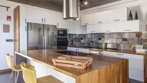 Una cucina moderna con mobili bianchi, elettrodomestici in acciaio inossidabile e un'isola in legno.