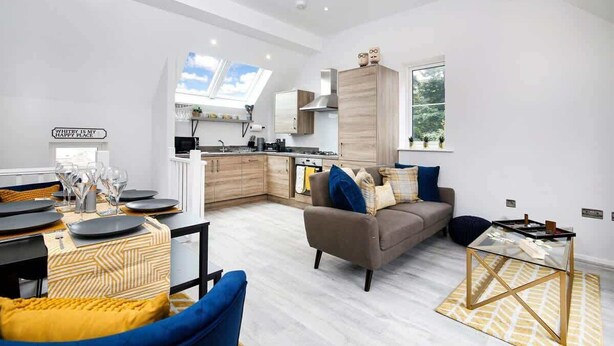 A modern living room with a sofa, coffee table, and dining area. - Host & Stay | Captain's Retreat (Whitby)