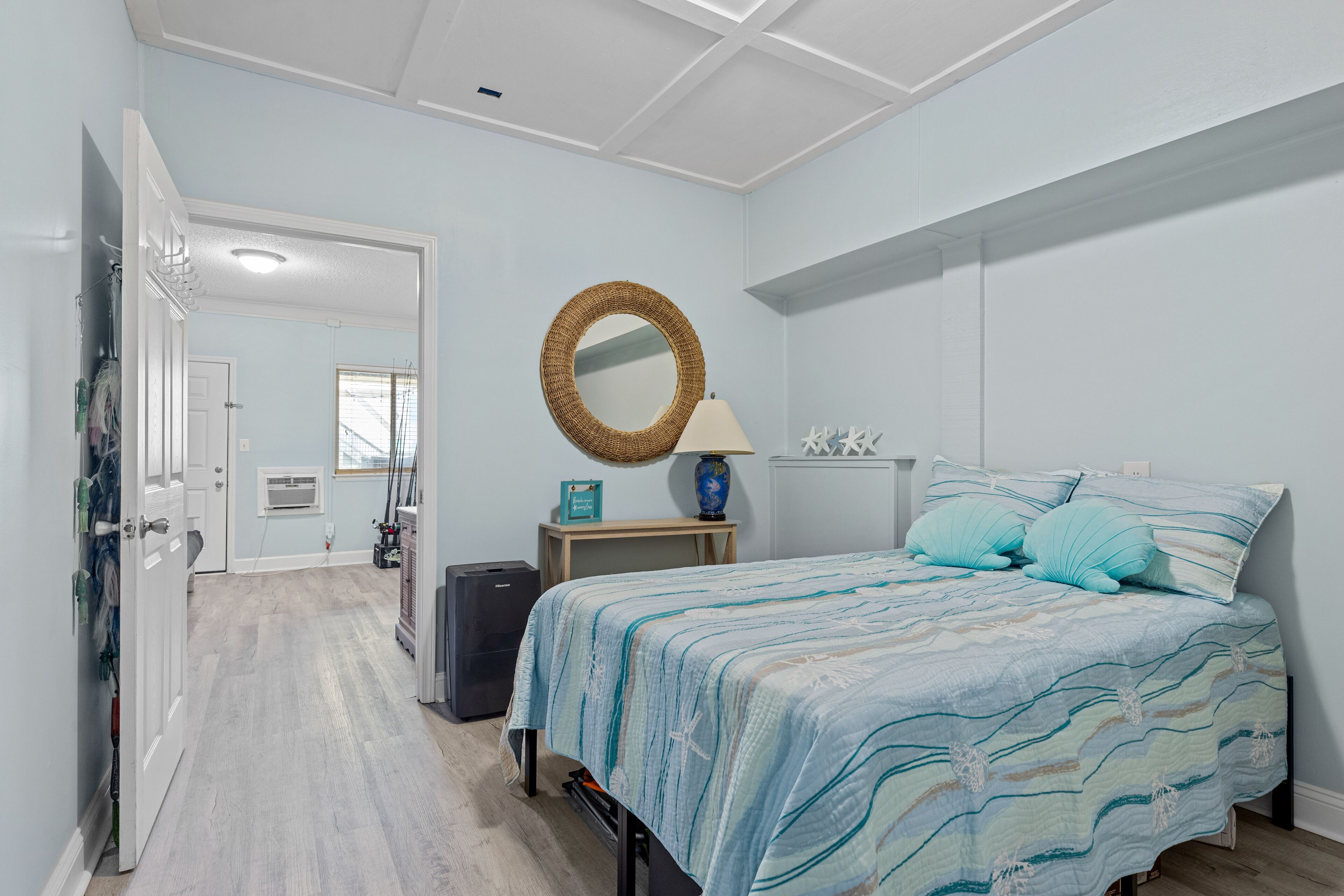 A bedroom with a bed, a round mirror, a lamp, and a small table.