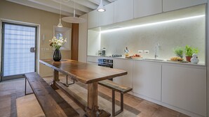 A modern kitchen with a wooden bench, a built-in oven, and a large island with a sink. - Ca' Minore Secret Garden (Venice)