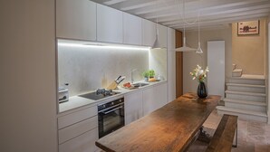 A modern kitchen with white cabinetry, a wooden countertop, and a built-in oven. - Ca' Minore Secret Garden (Venice)