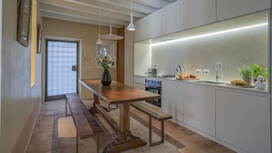 A modern kitchen with a wooden bench, white cabinets, and a large island with a sink and countertop. - Ca' Minore Secret Garden (Venice)