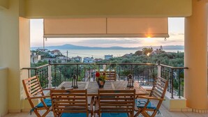 A balcony with a table and chairs, overlooking a scenic view of a body of water and distant mountains. - Palaiochora Retreat - Sea Sunset Rooftop (Avia Kalamata)