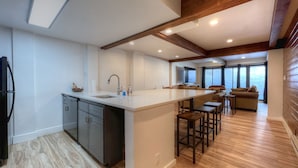 A modern kitchen with a central island, built-in appliances, and a dining area with bar stools.