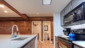 A modern kitchen with wooden accents, a dishwasher, a microwave, and a kettle.