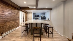 A modern kitchen with dark cabinets, a central island, and a dining area with wooden chairs and tables.