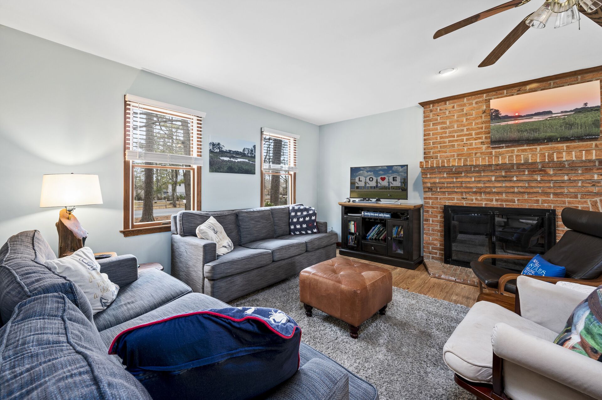 A living room with a sofa, ottoman, and armchair, a fireplace, and a TV.