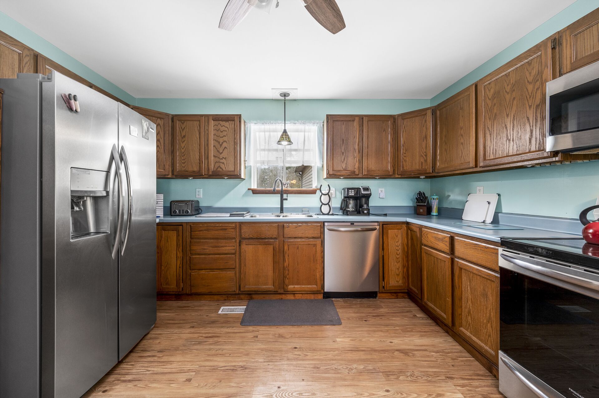 A kitchen with wooden cabinets, a stainless steel refrigerator, a dishwasher, a microwave, and a coffee maker.