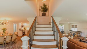 Eine Treppe mit Holzbodenstufen und schwarzen Spindeln, die zu einer Zwischenebene mit einem Blumentopf führt.