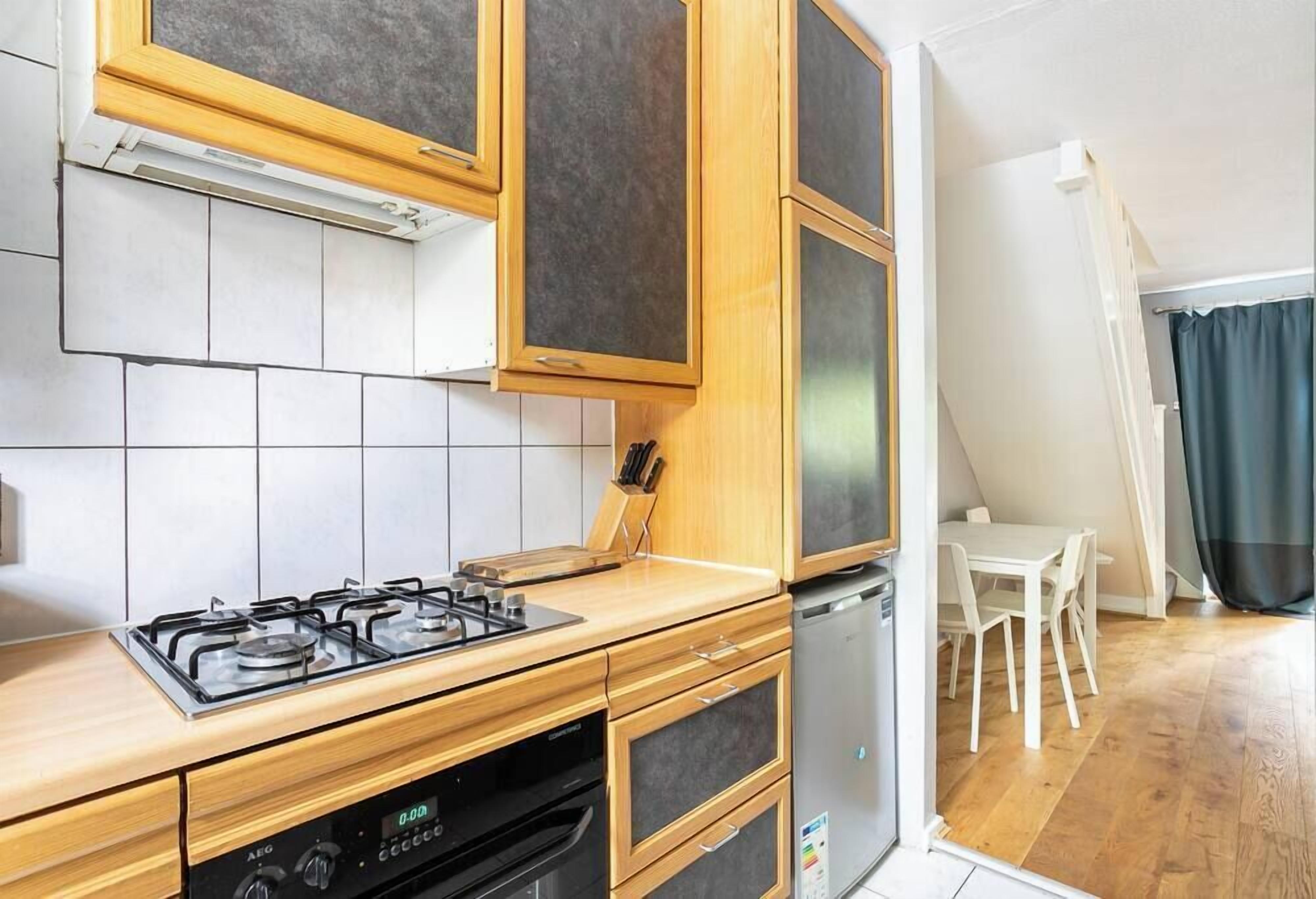Cuina compacta amb fornel, forn i rentaplats. Zona de dinar amb taula i cadires.