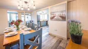 A dining area with a wooden table set for four, a chandelier, and a potted plant. - Eastgate Cottage and Hideaway, Salthouse, Norfolk (Salthouse)