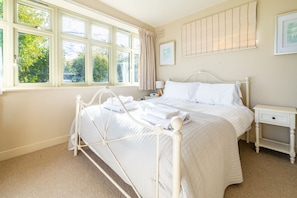A bedroom with a bed, bedside table, and a window with curtains. - Eastgate Cottage and Hideaway, Salthouse, Norfolk (Salthouse)
