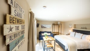 A cozy bedroom with a bed, bedside table, and a wall with a wooden sign. - Eastgate Cottage and Hideaway, Salthouse, Norfolk (Salthouse)