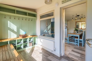 A room with a wooden bench, a radiator, a window with a view, and a dining area with a table and chairs. - Eastgate Cottage and Hideaway, Salthouse, Norfolk (Salthouse)