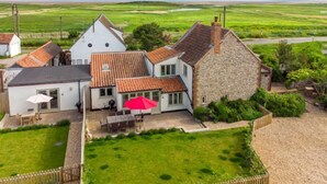 A rural house with a stone and tiled roof, a fenced yard, and a view of the countryside. - Eastgate Cottage and Hideaway, Salthouse, Norfolk (Salthouse)