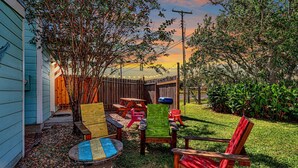 Un patio trasero con terraza de madera, mesa de picnic y sillas.