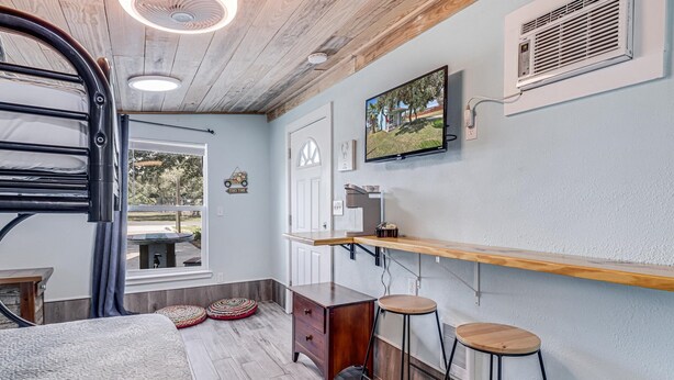 Cocina compacta con encimera de madera, horno empotrado y televisor montado en la pared.
