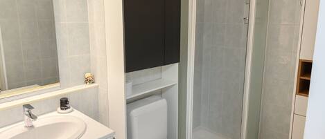 Un bagno con lavandino, water e cabina doccia, tutti bianchi.