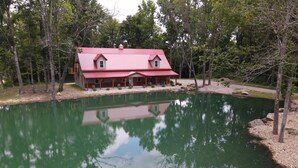 A house with a red roof and a pond in front.