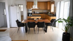 Una cucina moderna con mobili in legno, un'isola centrale e un'area pranzo con tavolo e sedie nere.