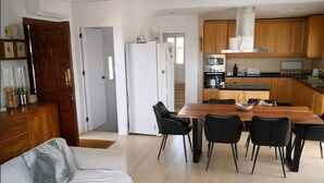 Una cucina moderna con mobili in legno, un tavolo da pranzo con sedie e un frigorifero.