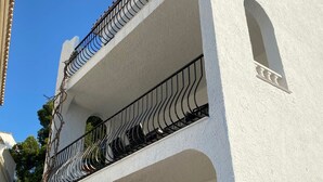 Un edificio bianco con un balcone caratterizzato da ringhiere in ferro battuto nero e una piccola finestra ad arco.