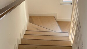 Una scala in legno con pareti bianche e una finestra in cima.