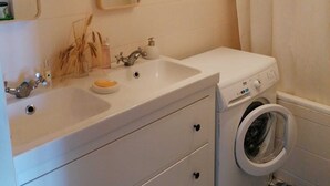 A bathroom with a sink, mirror, and washing machine. - Location 31 Juillet au 15 Aout (Paris)